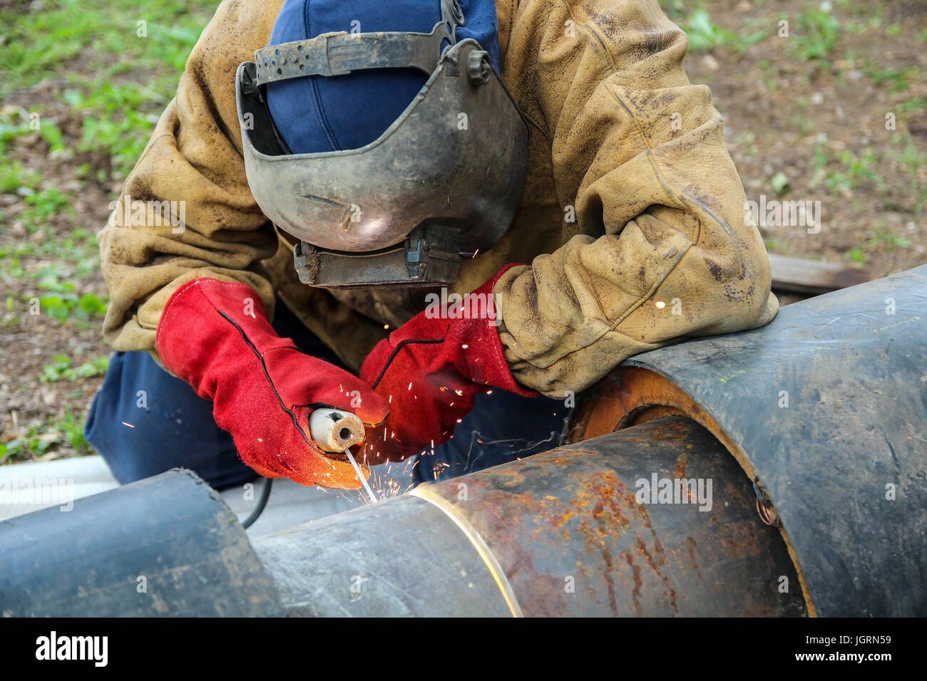 Welder cutting and preparing steel outdoors